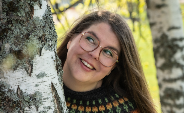 Riikka kurkkaa puun takaa